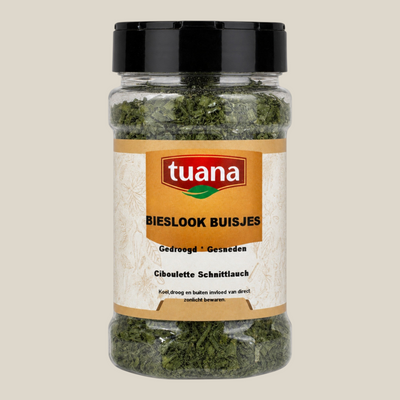 TuanaShop BV gedroogde bieslook buisjes in een doorzichtige voorraadpot met zwart deksel op een zwarte achtergrond.