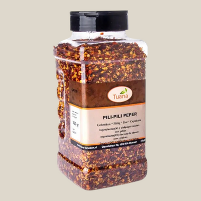 TuanaShop BV Pili Pili peper in een doorzichtige voorraadpot met gebroken rode chilipepervlokken en zwarte dop